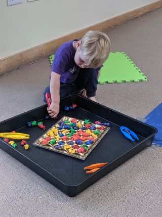 A child sorts coloured items into a chocolate box as part of an Earth Day activity