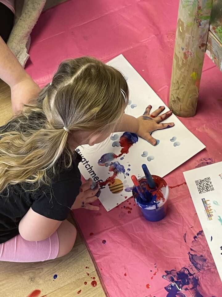 A child uses their hand to make marks on a worksheet for Children's Activity Week