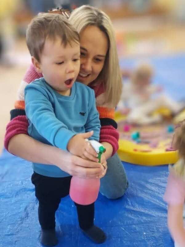 A child and mother play with a spary bottle at Little Learners South Colchester