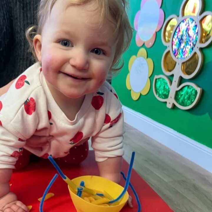 A little girl plays at the Little Learners Playspace in Ashington, sequin flowers sparkle on the wall behind her. 