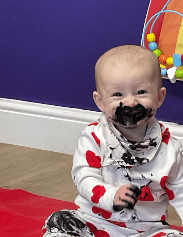 A baby in ashington wears a onesie covered in black paint at Playspace Ashington