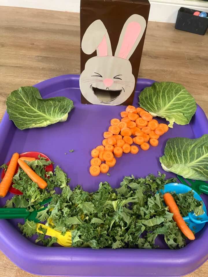 Feed the Easter Bunny craft for children at Little Learners Playspace Ashington. A cardboard bunny sits in a tuff tray surrounded by vegetables.