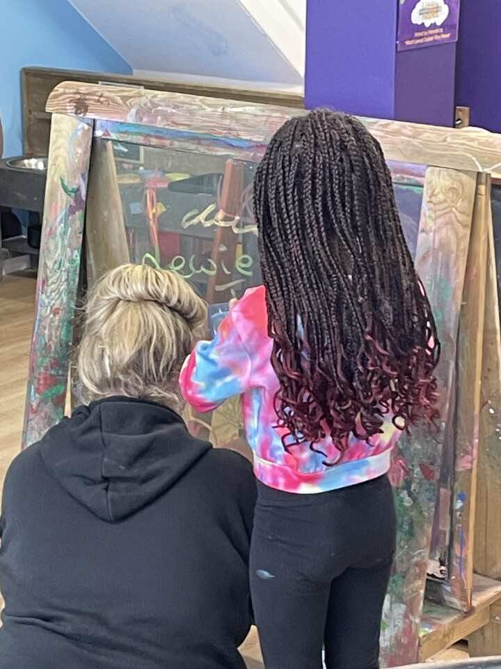 HAF Activities - a child paints with their mum on a wooden easel