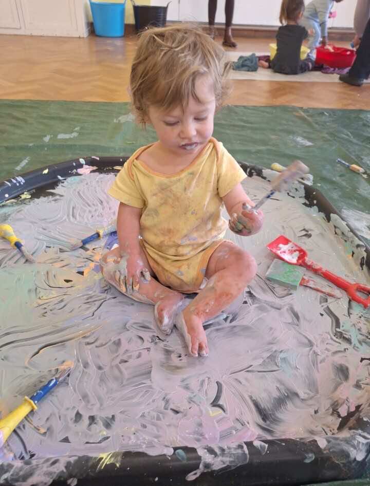 Baby sitting in tray of paint