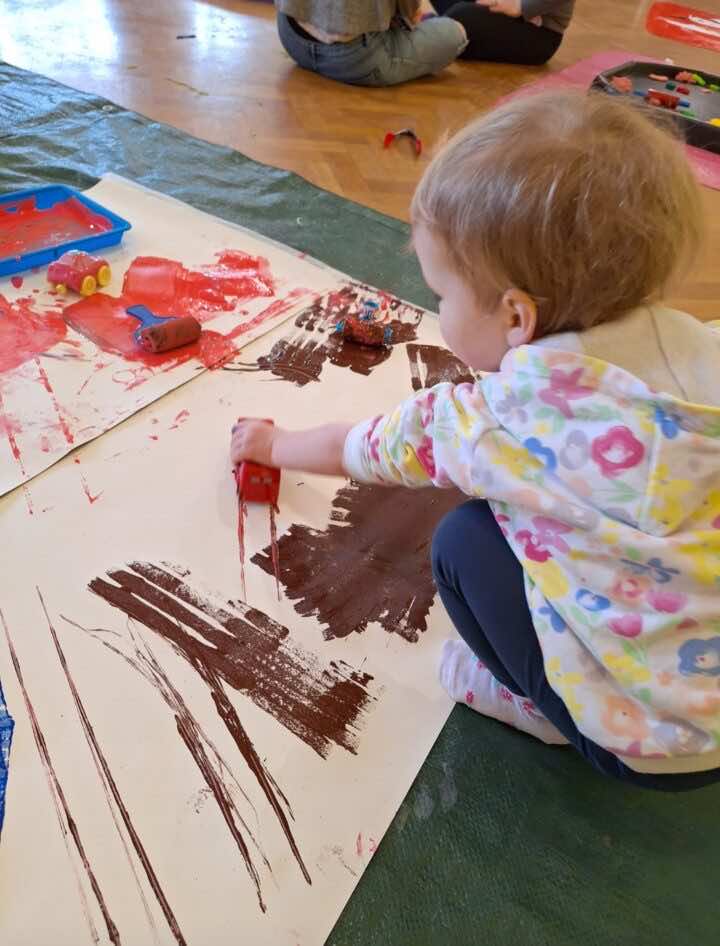 Toddler pushing a car through paint