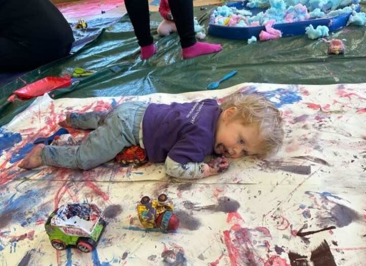 Toddler laying on a painted piece of paper exhausted