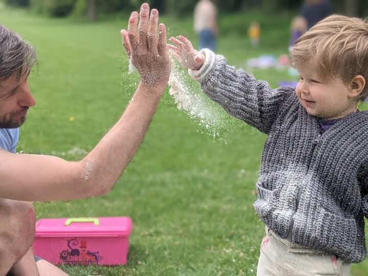 A child and their father give each other a high 5 at a messy play class